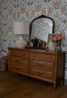 a wooden dresser sitting next to a wall with a mirror on it's side