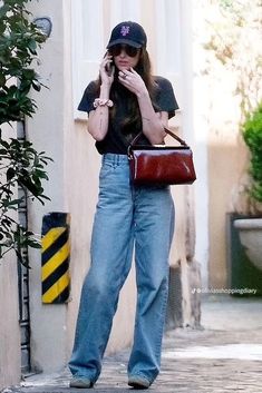 a woman is talking on her cell phone while walking down the street with a handbag