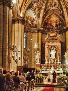 the bride and groom are standing at the alter in front of the altar as people look on