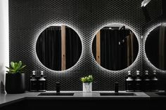 a bathroom with three round mirrors on the wall and two planters in front of it