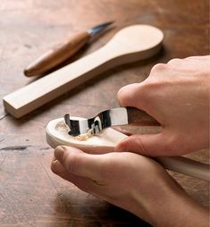 a person using a pair of scissors to cut something out of a piece of wood