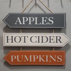 three signs hanging on the wall that say apples, hot cider and pumpkins