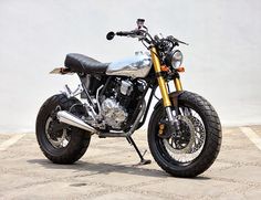 a motorcycle is parked in front of a white wall and cement flooring with no one around it