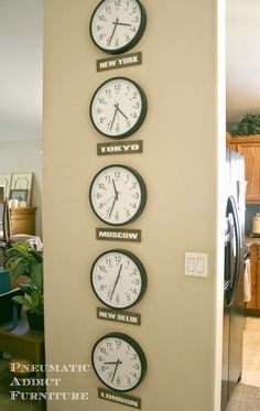 three clocks are on the wall in front of a refrigerator and stove top freezer