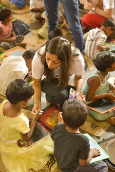 a group of children sitting on the floor in front of a woman