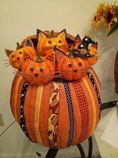 a group of orange cats sitting on top of a pumpkin shaped potted planter