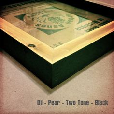 a wooden frame sitting on top of a counter next to a black box with the words di - pear two tone black