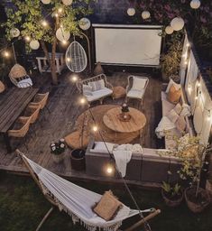 an outdoor deck with hammock chairs and lights strung from the ceiling above it