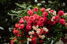 a bunch of red and pink roses in a vase on a table with greenery