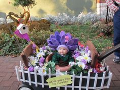 a doll sitting in a flower pot with fake flowers on the ground next to it