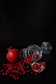 pomegranates and glass containers on a black background, with one cut in half