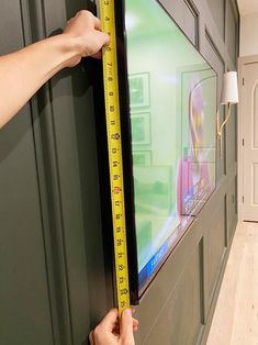 a person measuring the height of a television screen with a tape measure on it's side