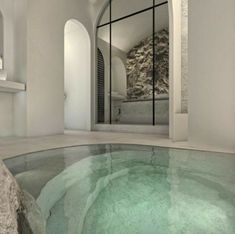 an indoor swimming pool in the middle of a room with large windows and stone walls