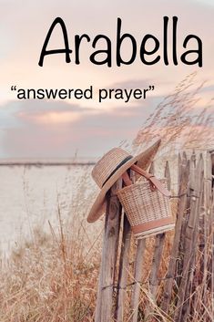 a straw hat on top of a wooden fence next to the ocean with text that reads, arabella answered prayer