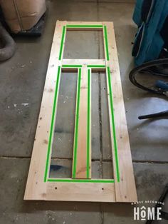 an unfinished window frame with green tape on the bottom and side panels cut in half