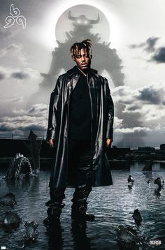 a man standing in the water with his hands on his hips and wearing a black coat