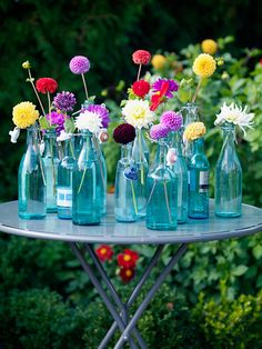 colorful flowers are in blue glass bottles on a table