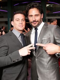 two men standing next to each other in front of a red carpeted floor and one pointing at the camera