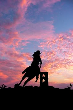 the silhouette of a cowboy riding a horse in front of a pink and blue sky