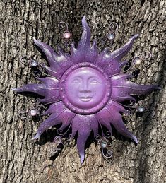 a purple sun face sitting on top of a tree