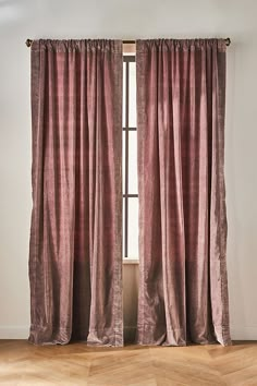 an open window with pink curtains and wooden floors