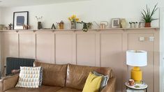 a living room with a brown leather couch and yellow lamps on the shelves above it