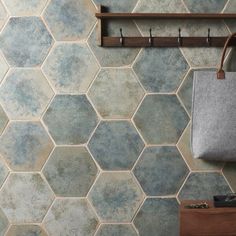 a bathroom with hexagonal tiles on the wall and a wooden shelf above it