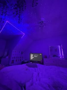 a bed room with a tv and purple lights on the ceiling in front of a window