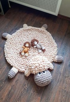 a crocheted sheep rug with stuffed animals on the floor in front of a radiator