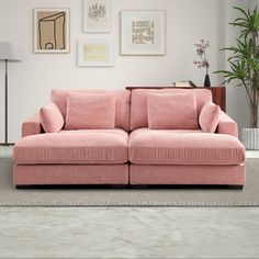 a living room with pink couches and pictures on the wall above it, along with a rug