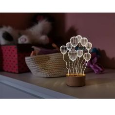 a wooden table topped with a lamp that has flowers on it and some baskets in the background