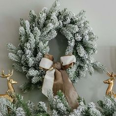 a christmas wreath with two deer figurines in front of it