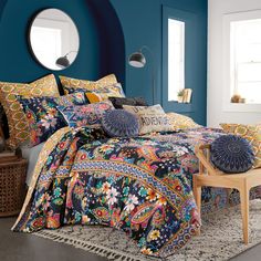 a bedroom with blue walls and colorful bedding