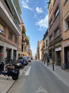 a street lined with parked scooters next to tall buildings on either side of the street