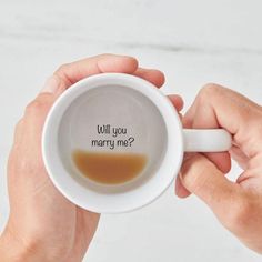 someone holding a coffee mug with the words will you marry me?