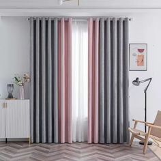 a living room with grey and pink curtains, a wooden chair and a white cabinet