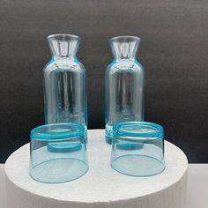 two blue glass vases sitting on top of a white stand with rings around them