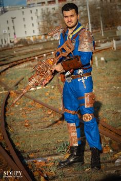 a man dressed in blue and gold standing on train tracks