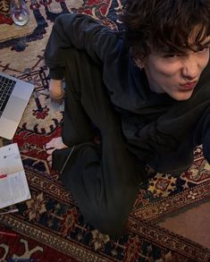 a woman is sitting on the floor with her laptop and papers in front of her