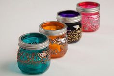 four different colored mason jars lined up next to each other on a white table top