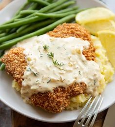 a white plate topped with mashed potatoes covered in gravy and green beans