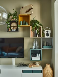 a flat screen tv sitting on top of a white entertainment center next to a vase