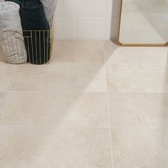 a bathroom with white tile floors and a gold framed mirror on the wall next to it