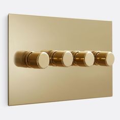 three round knobs on the side of a wall mounted light switch in gold and white