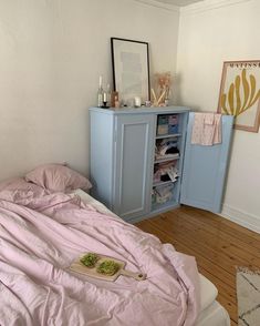 an unmade bed in a bedroom with pink sheets and blankets on the bedspread