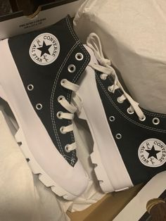 a pair of black and white converse sneakers on top of a cardboard box with other items