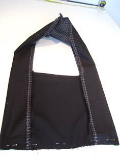 an open black bag sitting on top of a white table next to a pair of scissors