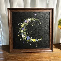 a wooden frame holding a painting with flowers on it and a potted plant next to it