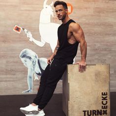 a man sitting on top of a wooden crate next to a wall with a painting