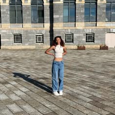 a woman standing in front of a building with her hands on her hips and looking at the camera